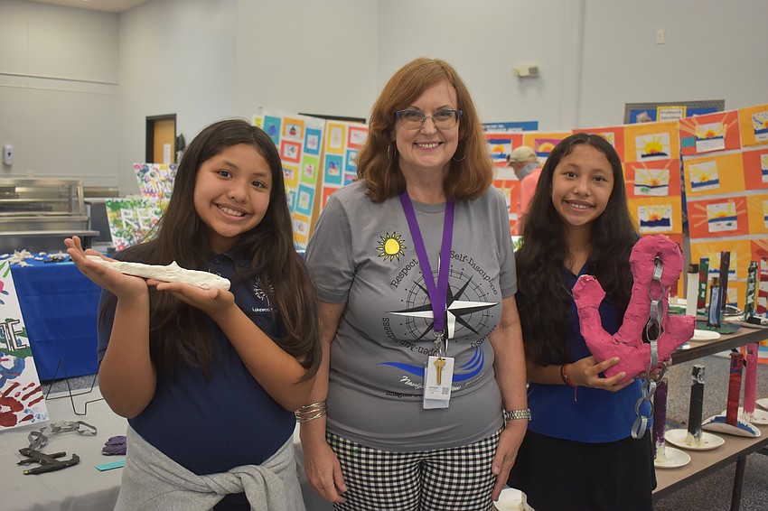 Fourth grader Evalyn Perez, art teacher Gina Gretz and sixth grader Yaslin Perez pose with their artwork.