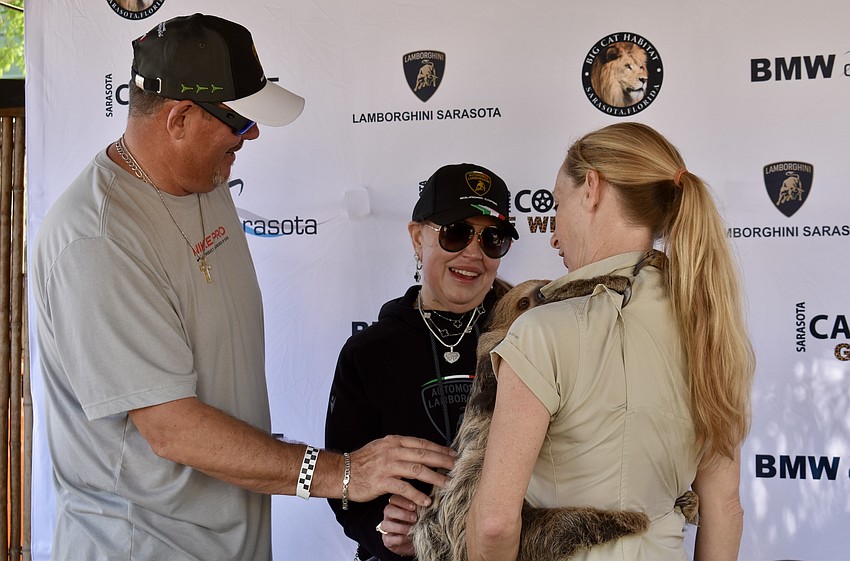William and Laura Hamby step away from their 2024 Italian Huracan Tecnica Lamborghini to pet a sloth. Danielle Rosaire is holding the 1-year-old sloth.