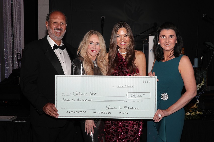 Philip Tavill, Mary Gratehouse, Amy Hoskins and Jessica Rogers accept a check from Women in Philanthropy.