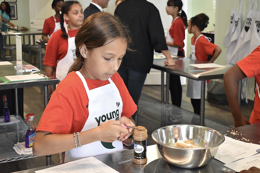 Ryker, a fourth grader, measures out cinnamon.