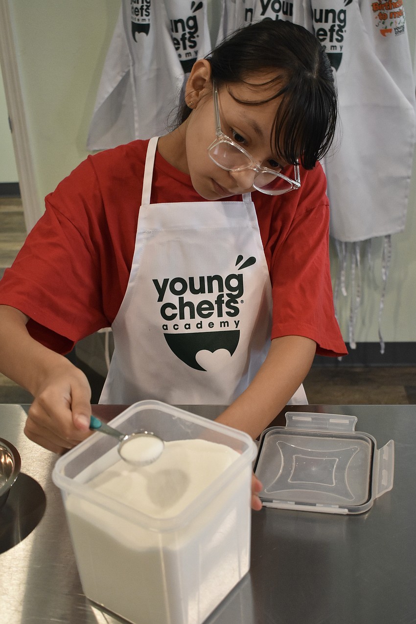 Arianny, a sixth grader, measures out an ingredient for the cakes.