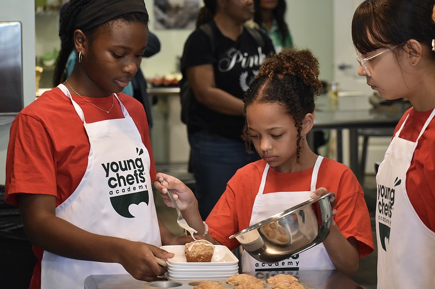 Emma, a sixth grader, Gloria, a fourth grader, and Arianny, a sixth grader, add icing to a coffee cake.
