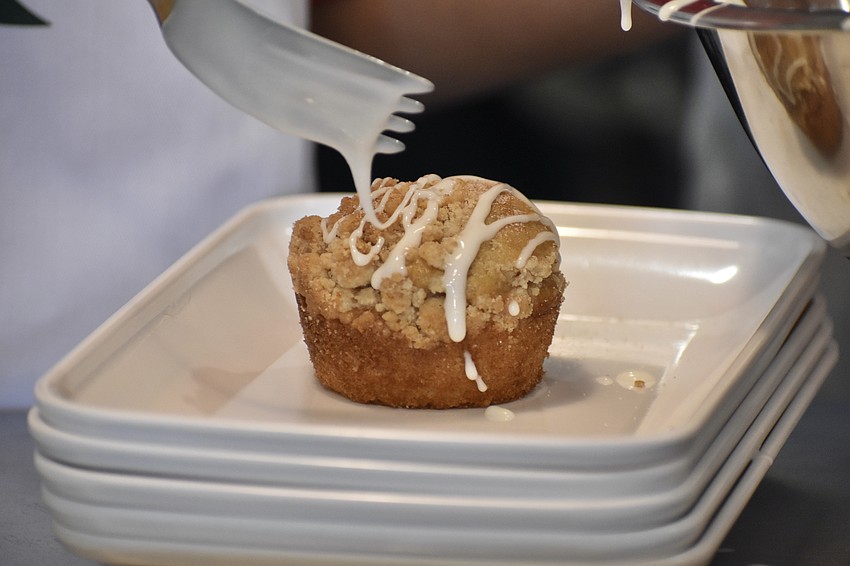 A member of Girls Inc. spreads icing across a coffee cake.