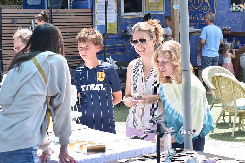 Phoebe Buissens, 15, talks with Cormack Phillippi, 12, his mother Kerry Sheridan, and his sister Audrey Phillippi, 15, as they browse the market.