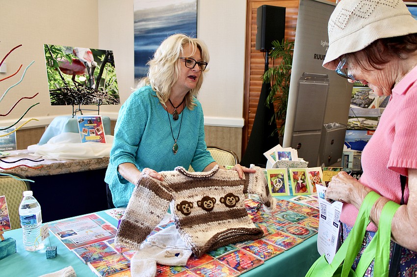 Brigette Kubin, owner of the newly opened Three Island Monkeys, shows off the new sweaters the boutique is carrying during this year's 