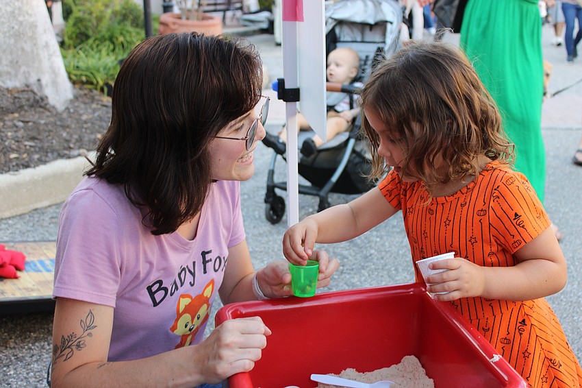 Baby Fox Academy teacher Kayla Romanowiz plays in the kinetic sand with Sarasota 2-year-old Summer Segelman during the Block Party and Club Day at Main Street at Lakewood Ranch.