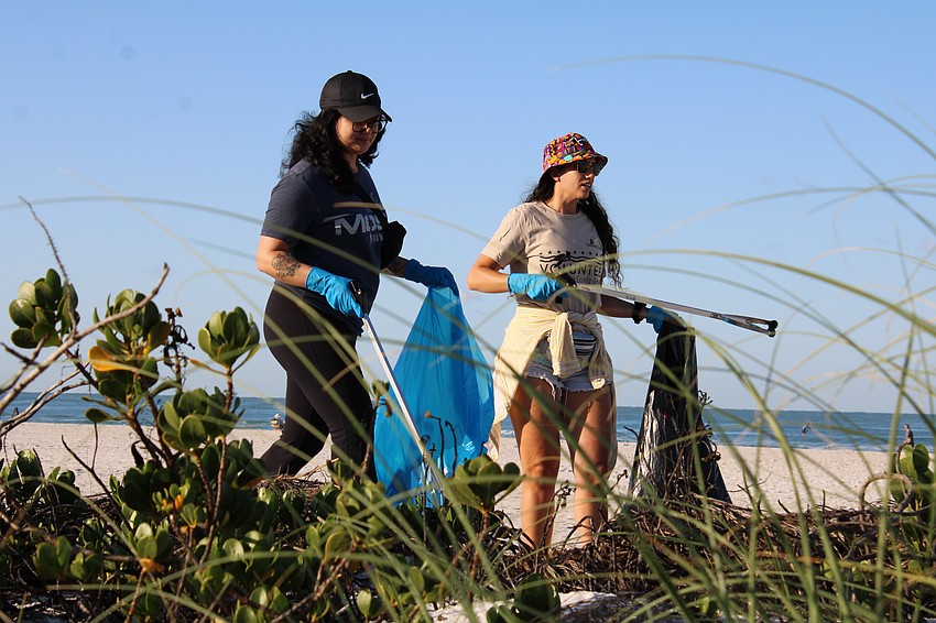 Stephanie King and Casey Anderson comb beachside vegetation at Lido Beach as part of the Greatest American Cleanup.