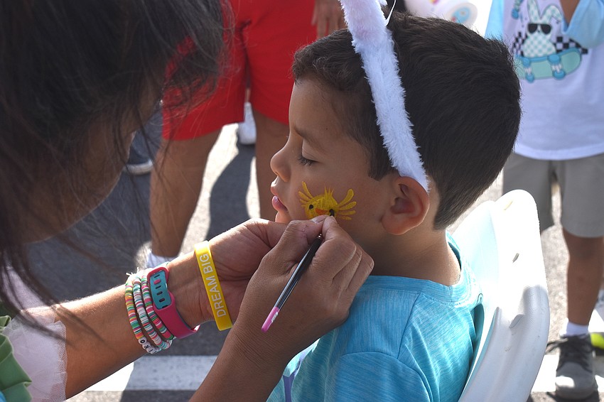 Christian Diaz, 5, has a chick painted on his face by Akiko Campbell of Akiko Graphics. Campbell has painted faces for 18 years.