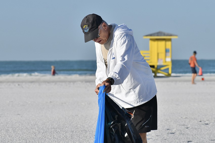 Bob Evans puts trash in a bag.