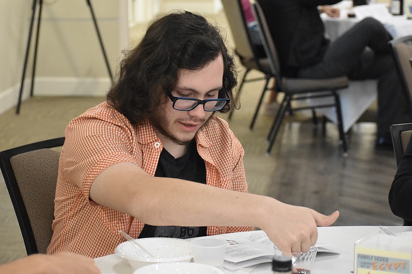 Jake Pullam joins participants in removing ten drops of wine from his cup to represent the ten plagues.