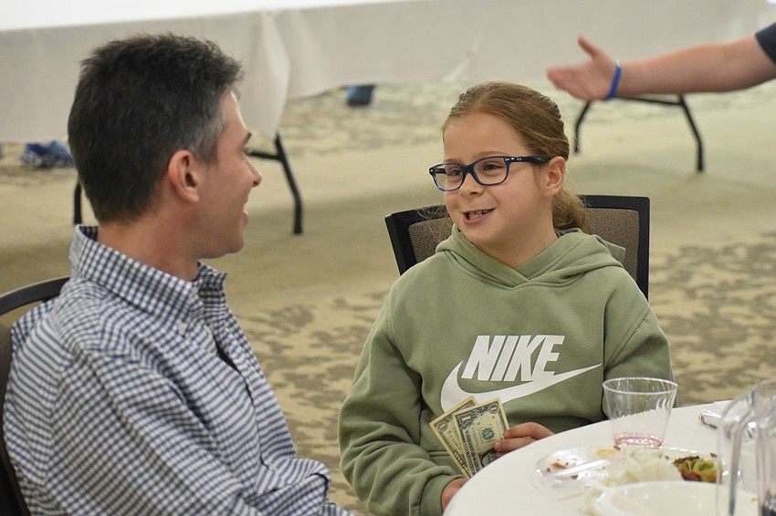 Ryan Jawitz talks with his daughter Norah Jawitz, 9, who has just received a prize of dollar bills for finding Afikoman.