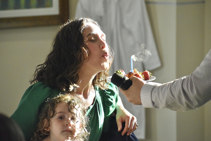 Shayna Shefrin holds Maya Shefrin, 2, as she blows out the candle on her birthday treat, a macaroon, presented by her husband Rabbi Michael Shefrin.