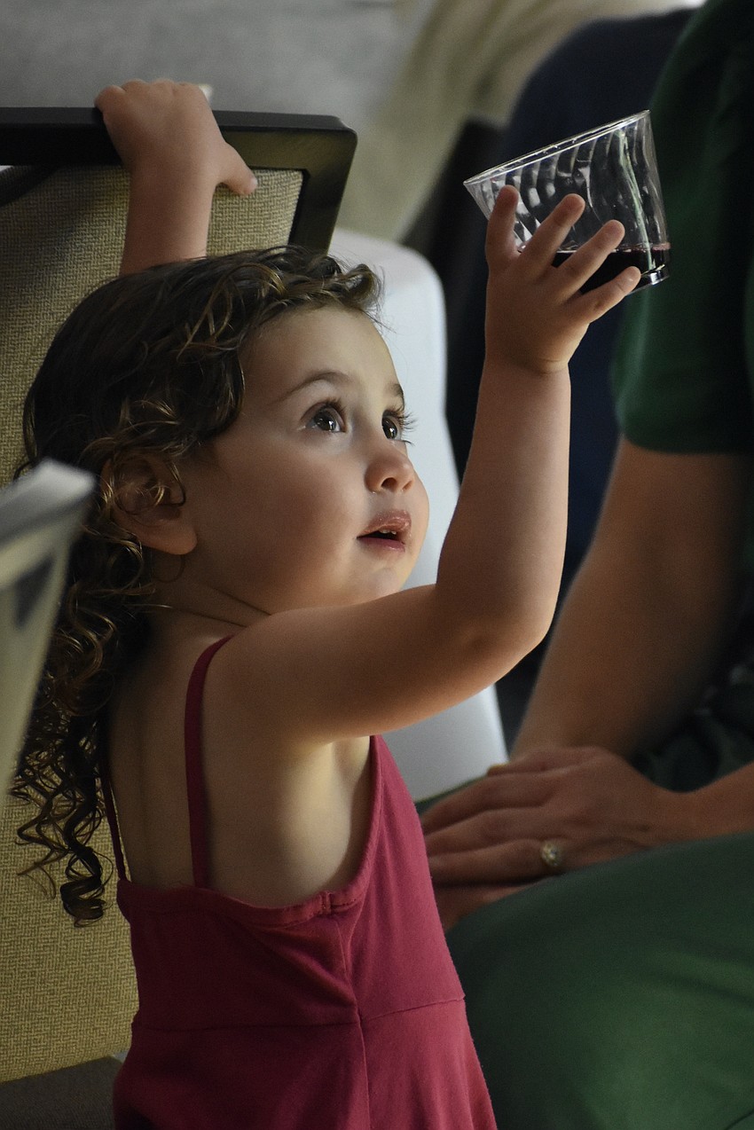 Rabbi Michael Shefrin's daughter Maya Shefrin, 2, holds the grape juice as it is blessed.