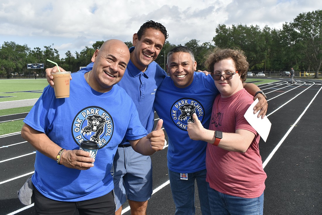 Staff members Cesar Huertas, Fredy Sepulveda Ramos, and Johan Guerrero gather with 12th grader Nicolo Moschini on the track.