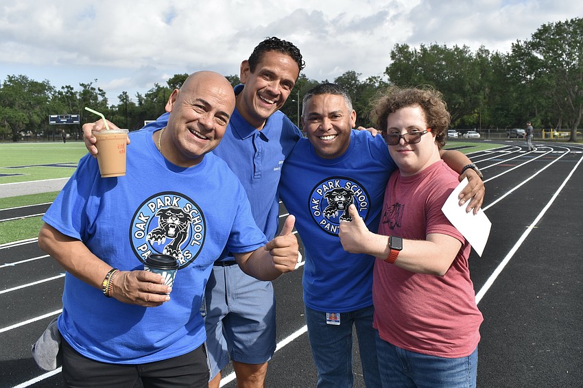 Staff members Cesar Huertas, Fredy Sepulveda Ramos, and Johan Guerrero gather with 12th grader Nicolo Moschini on the track.
