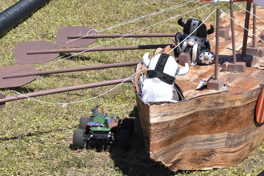 A race car passes under a viking ship.