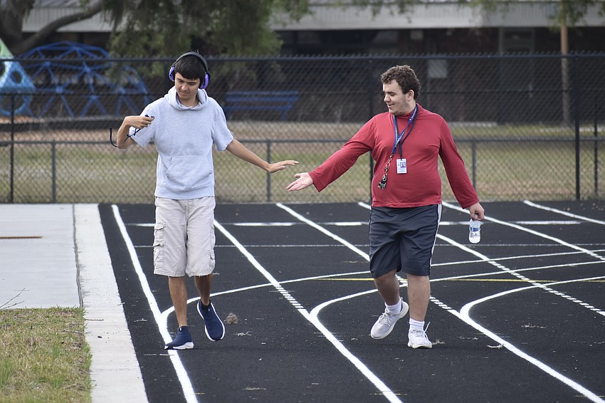 12th graders Vinnie Smith and Alex Langham slap hands after circling the tracj.