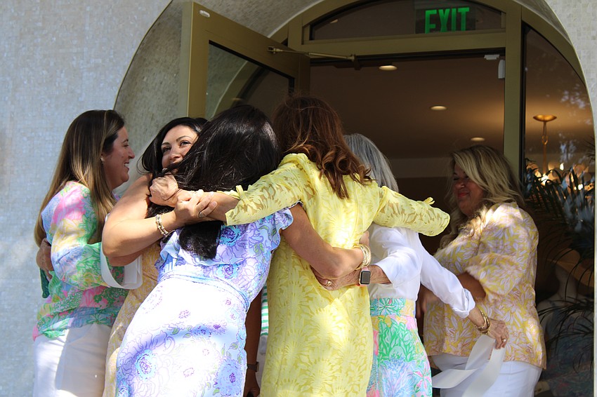 The team shares a group hug at the ribbon cutting.