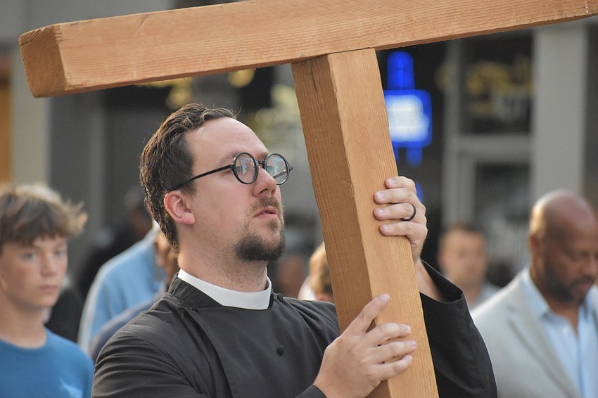 Rev. David Svihel carries the cross down Main Street.