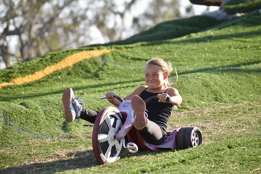 Lakewood Ranch's 7-year-old Olivia Johnson tears down a turf hill on a tricycle in games that were part of the Dakin Bull Bash.