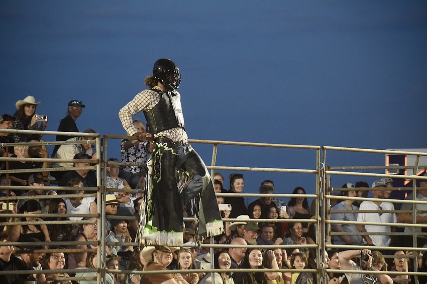 Eli Mosley jumps up on the fence to get away from the bucking bull in the arena during the Dakin Bull Bash.