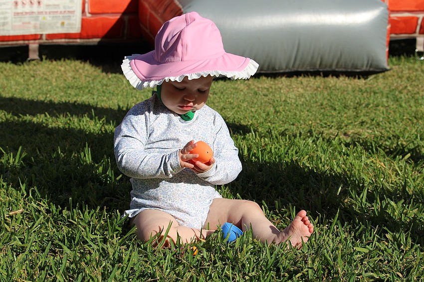 One-year-old Nell Doyle, accompanied by father Kevin, carefully inspects an orange Easter egg at Sand Cay.