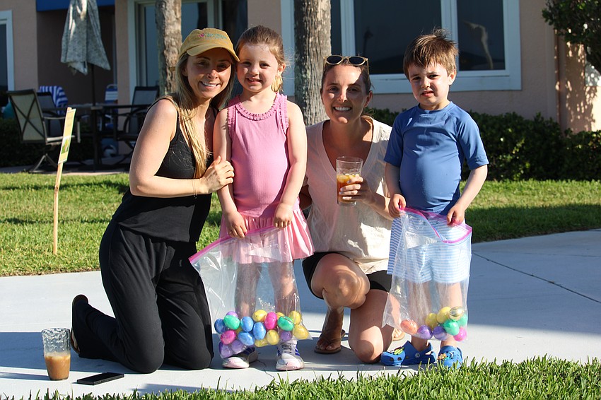 Charlie Doyle, 3, finds one of the golden eggs at Sand Cay. He enjoys Friday's festivities with sister Olivia, 5, mother Jen, and aunt Caroline Sims.