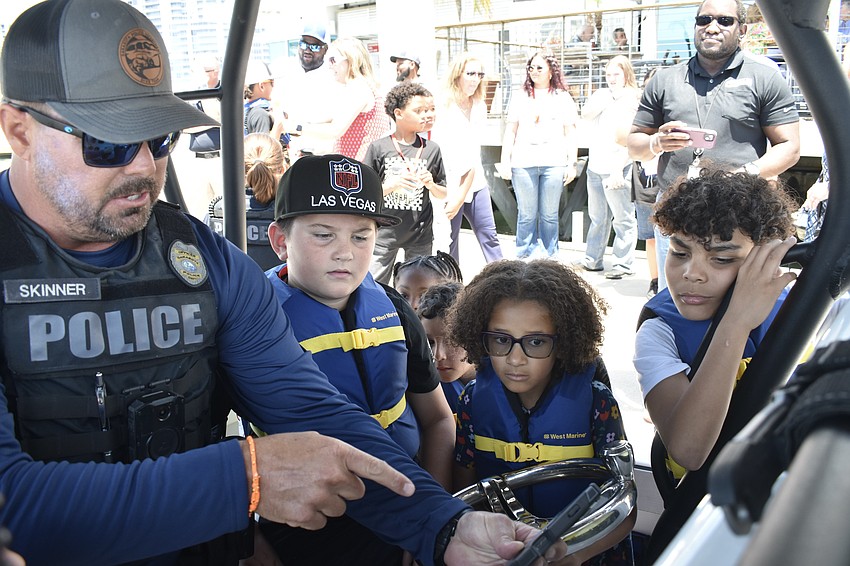 Marine Patrol Officer Michael Skinner shows a video of a boat rescue to Captain Harvey, 9, Eva Bennett, 6, and Preston Hilton, 10