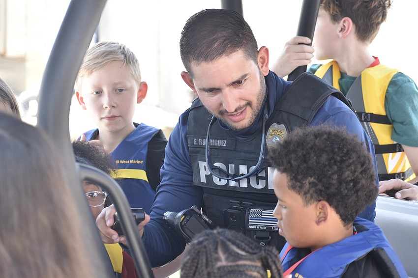 Officer Geno Rodriguez (center) speaks with kids including Nieko Scherry, 11,  and Messiah Louidor, 7.