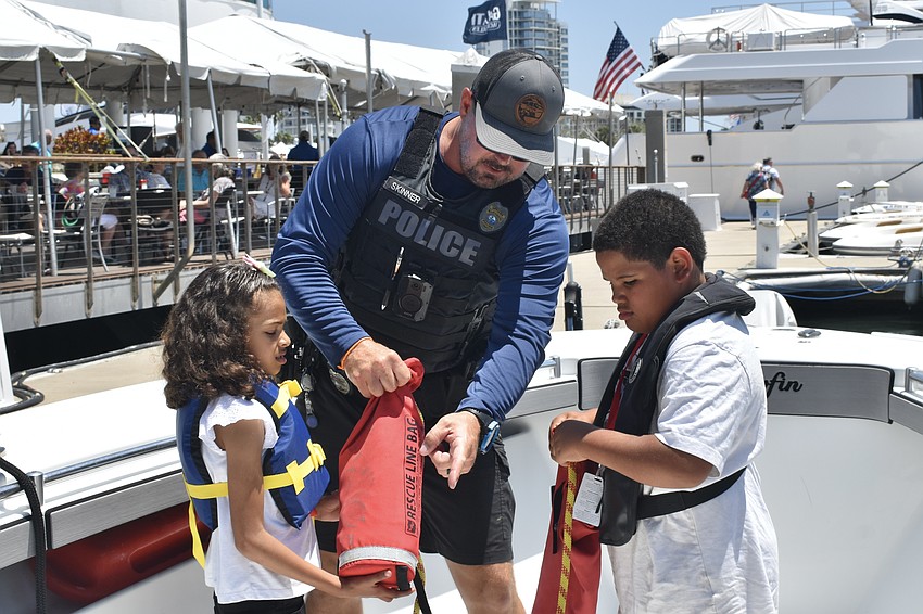 Analise Gallant, 7, Marine Patrol Officer Michael Skinner, and Messiah Louidor, 7, prepare to toss out a rescue bag.