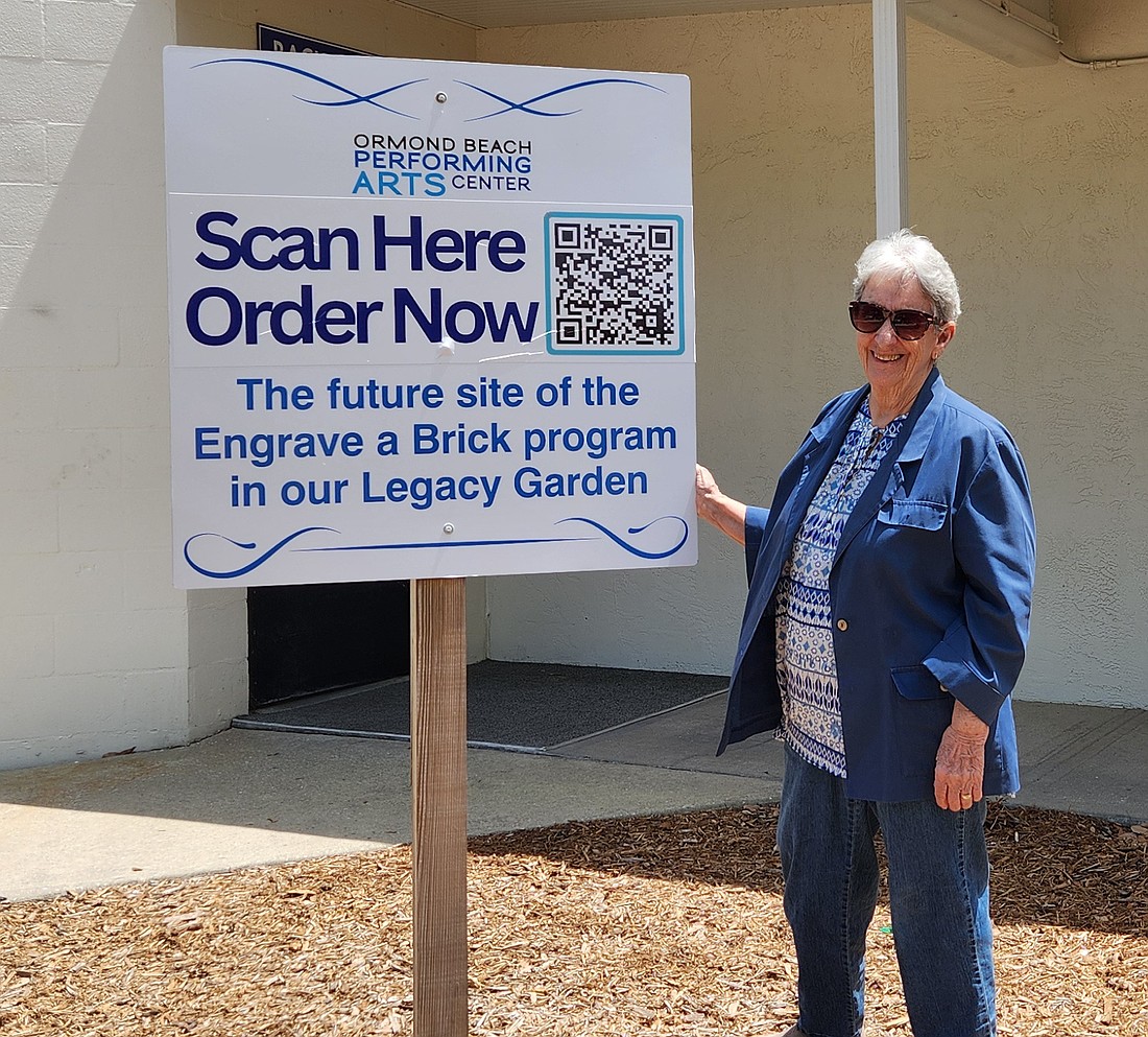 Lucy Jackman, president of the Friends of the performing Arts Center, stands next to a sign advertising the new brick fundraiser. Courtesy photo