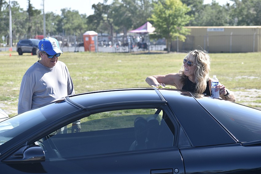 Andy Thompson talks with his friend Michele Kennedy as she cleans off her 1998 Pontiac Trans Am.