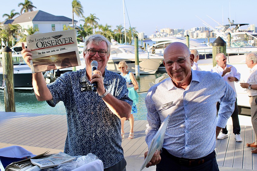 Vice Commodore Tony Britt and Commodore Michael Landis hold up a copy of 