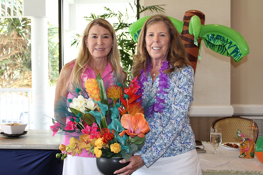 Incoming president of the Women's Golf Association of Longboat Key Mary Taylor presents outgoing president Lyn Haycock with a bouquet.