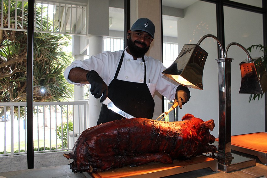 Yovishen Cavaree dishes up the roast pig at the Women's Golf Association of Longboat Key's luau-themed end-of-season party.