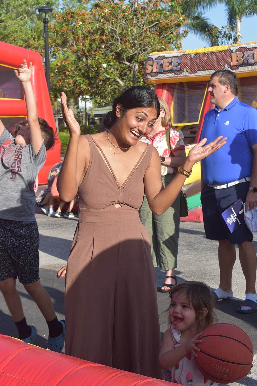 Kavita Tisdale takes a shot trying the basketball shooting game, with her daughter Alia Tisdale ready to be the next participant.