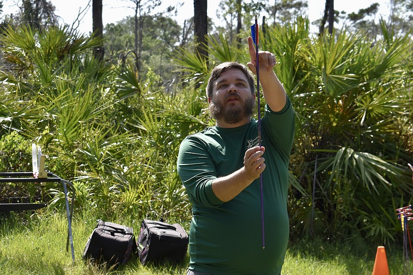 Aedan Stockdale, Education and Volunteer Divison Manager for Manatee County, points to the different colored feather on the arrow, which guides how the arrow is placed on the bow.
