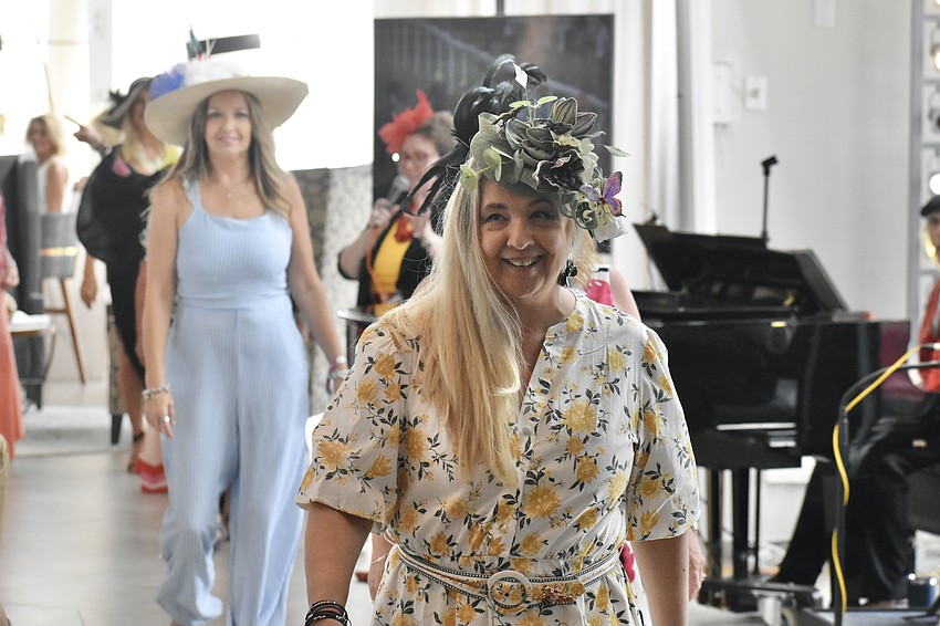 Participants in the hat contest walk across the room, with Michelle Nixon in front.