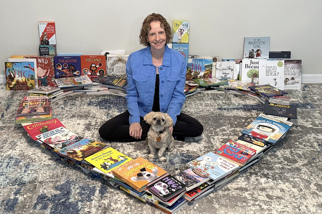 Felicia Donson and her dog, Jasper, sit surrounded by donated books.