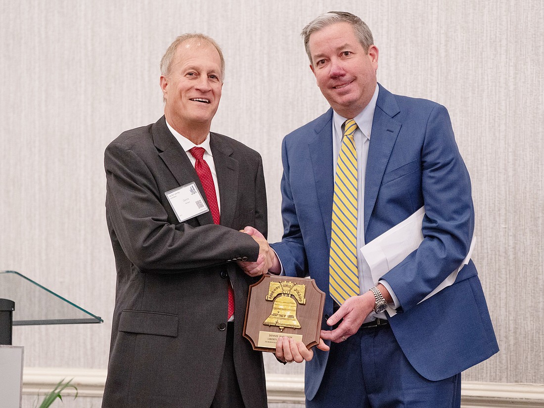 Dennis Harrison, left, chief development officer at Jacksonville Area Legal Aid, receives the Liberty Bell Award from Jacksonville Bar Association President Christian George.