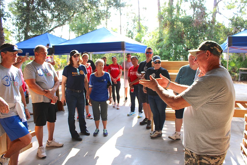 Volunteers listen to Beds for Kids co-founder Mark Coates (right) talk to them about the task ahead May 8 building beds.