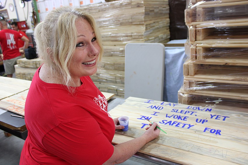Keller Williams Realtor Angela Stiner finishes up a Scripture verse during Red Day May 8 at the workshop of Mark Coates in East County.
