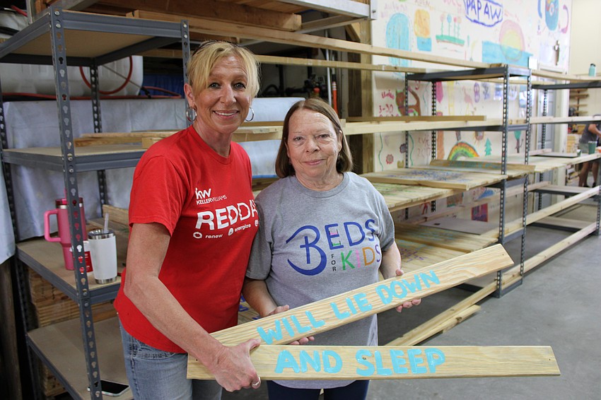 Keller Williams Coastal Living II CEO Rebecca Adams passes some bed slats to Brenda Coates, the wife of Beds for Kids co-founder Mark Coates.