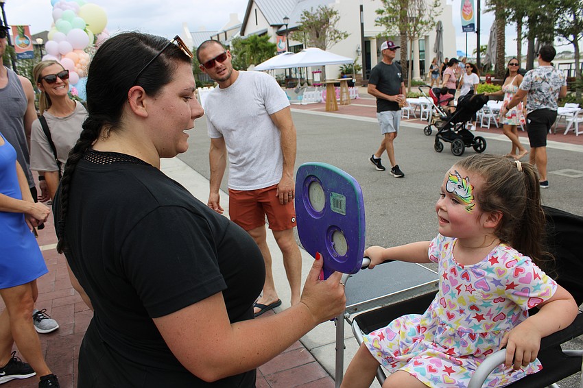 Face painter Gina Backhoff holds a mirror so 4-year-old Kenna Wichmer can check out the unicorn painted on her forehead during the Mother's Day event May 10 at Waterside Place.