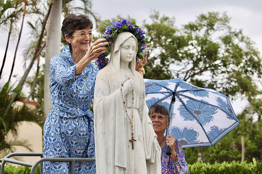Honoree Paula Sharp places the May flower crown atop the statue outside St. Mary, Star of the Sea, Catholic Church on Mother's Day.