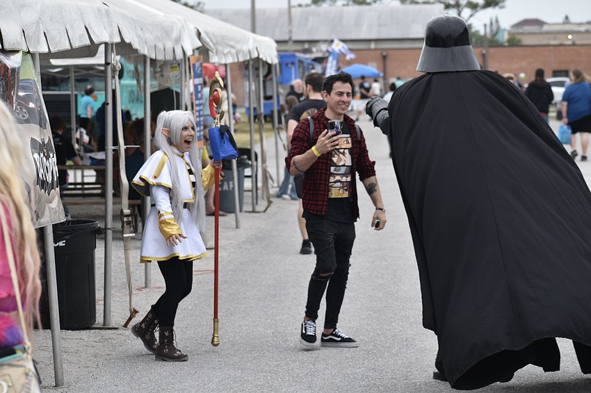 Jenny Romero and her husband Orlando Fernández meet Bryan Shuerger of the 501st Legion's Tampa Bay Squad, who dressed as Darth Vader.