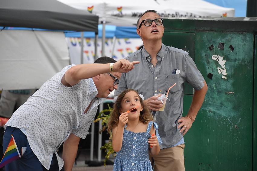 Scott Ditto, his daughter Olivia Ditto, 5, and husband Jim Ditto, stop while Olivia blows bubbles.