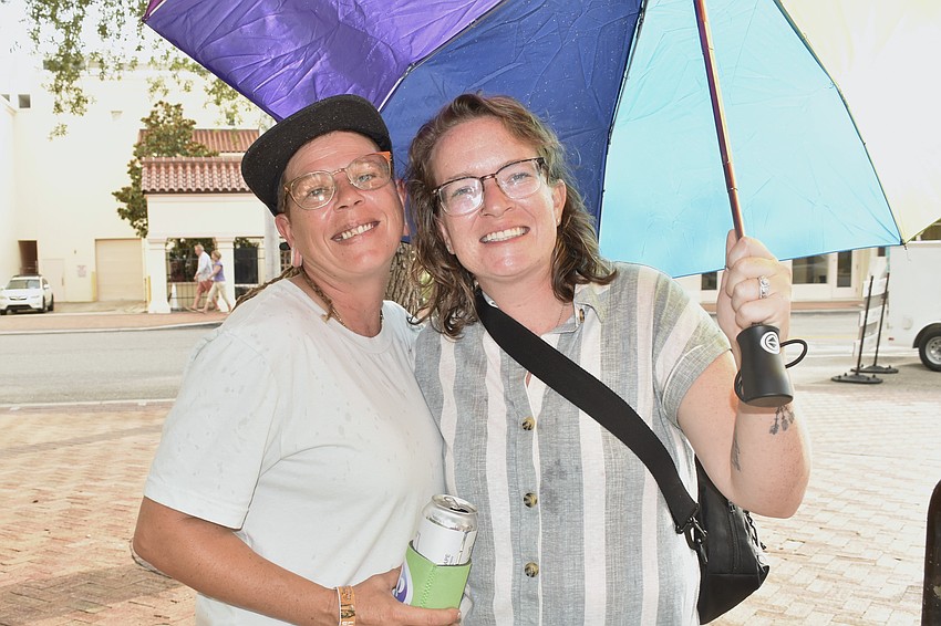 Bailey Bee and her fiancee Chelsea Hansen hold an umbrella during a light rain.
