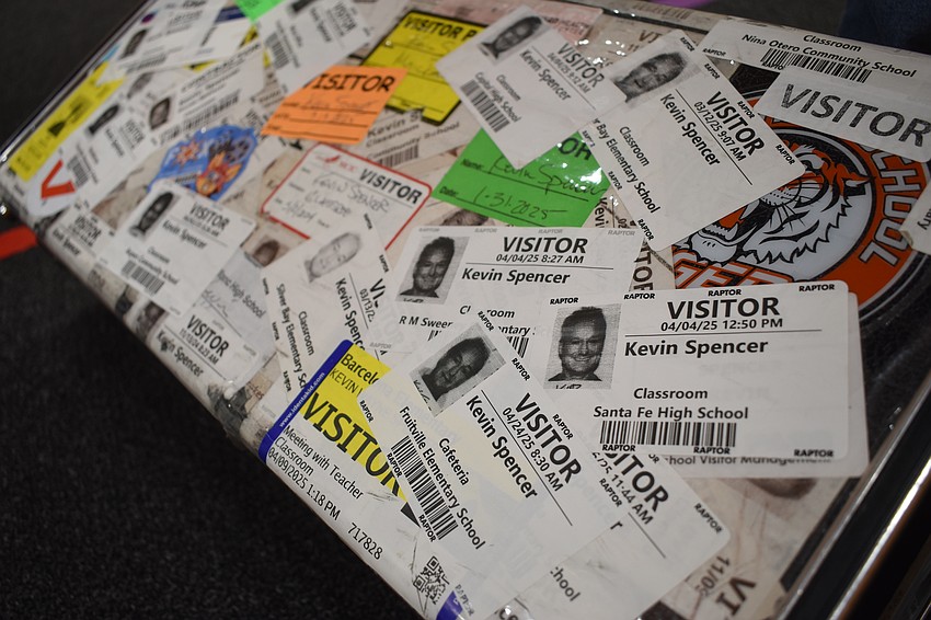 Kevin Spencer plasters his visitor stickers from schools across his suitcase.