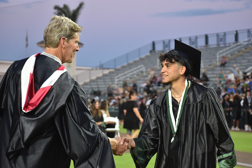 Victor Hugo Madalena receives a handshake as he receives his diploma. Madalena grew up in Brazil and came to Lakewood Ranch High as a freshman not knowing any English and now speaks it fluently.
